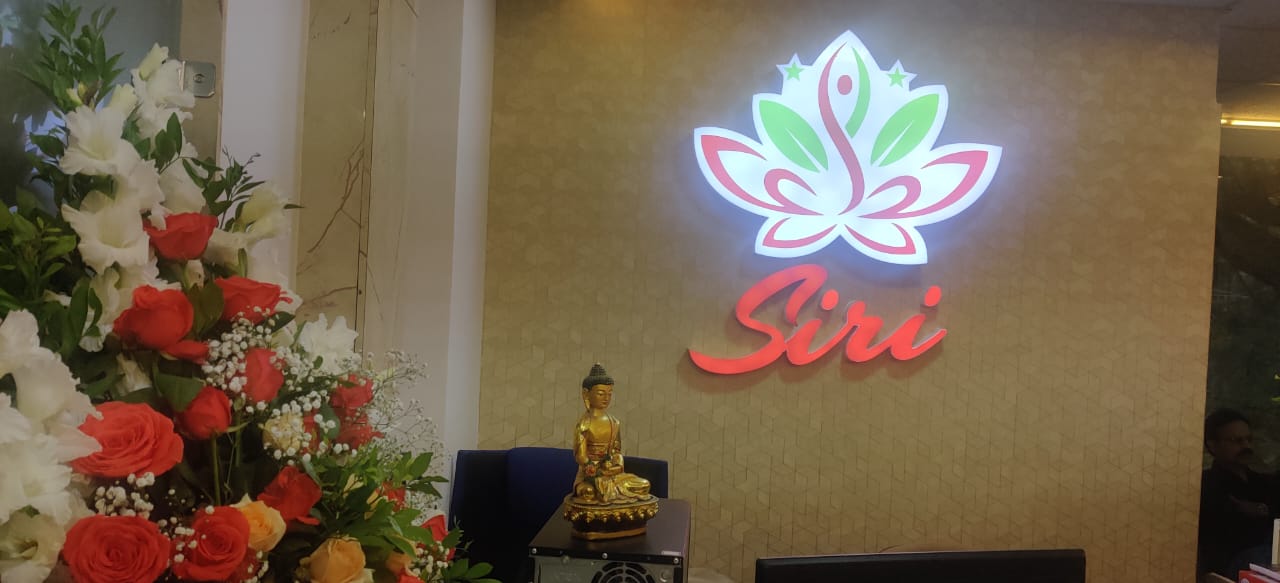 Illuminated Siri logo with decorative Buddha statue and floral arrangement